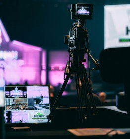 selective photo of camera with tripod and laptop computer turned on